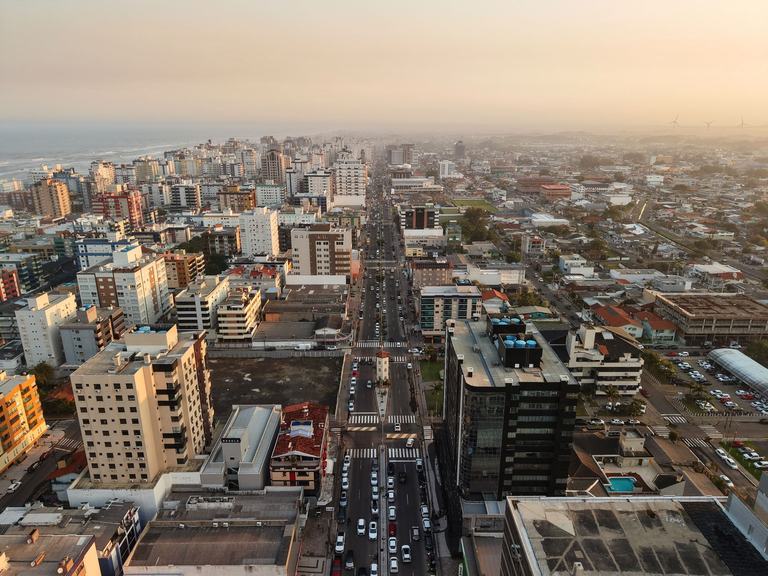 Avenida central de Capão da Canoa com comércio, edifícios e trânsito urbano